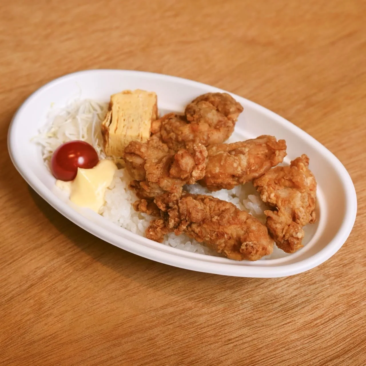 鶏唐揚げ丼弁当。ごはんの上に鶏の唐揚げとだし巻き玉子、キャベツを盛り付けた丼弁当