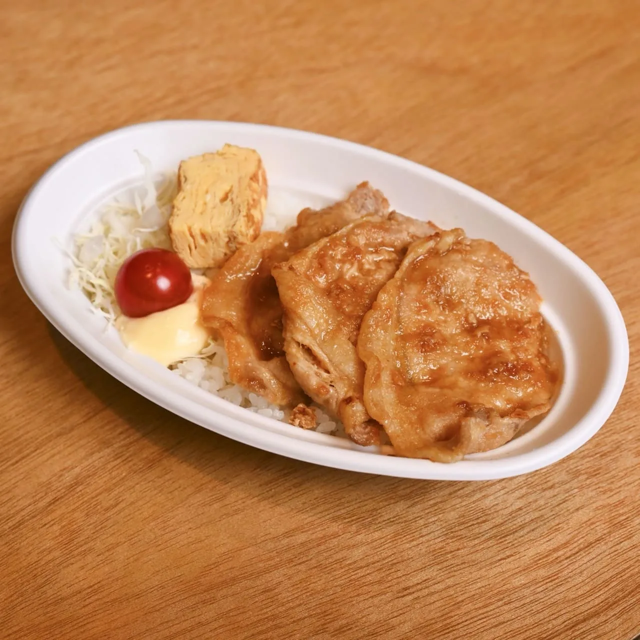 豚生姜焼き丼弁当。ごはんの上に豚の生姜焼きとだし巻き玉子、キャベツを盛り付けた丼弁当