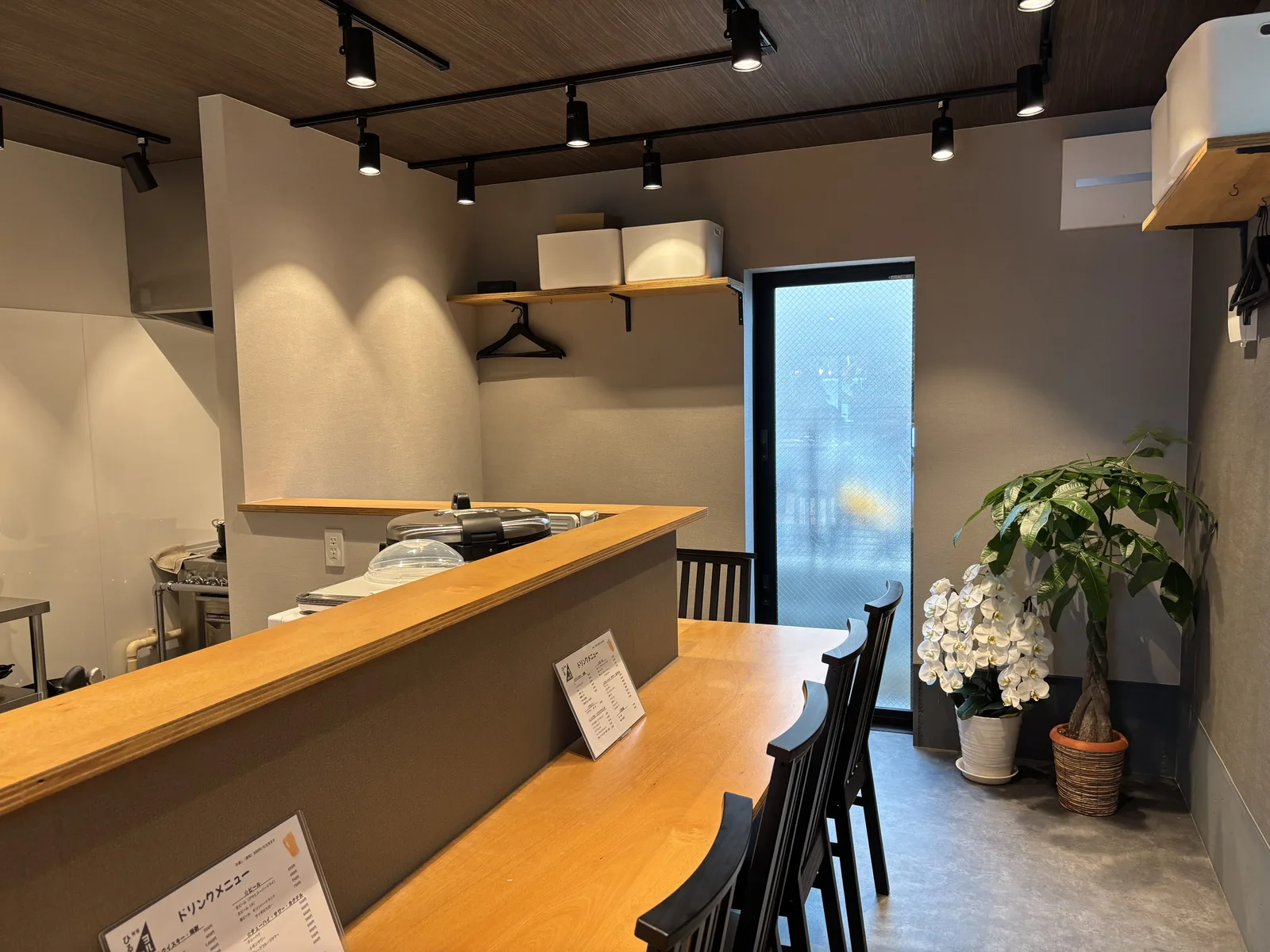 木のカウンターが続く、白とグレー基調の明るい店内